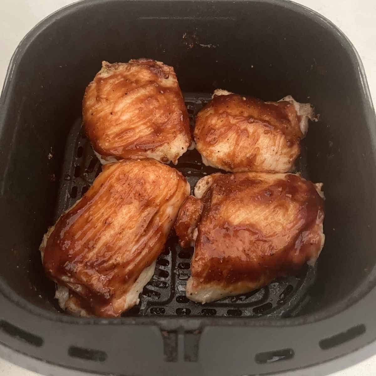 BBQ chicken thighs in air fryer basket.