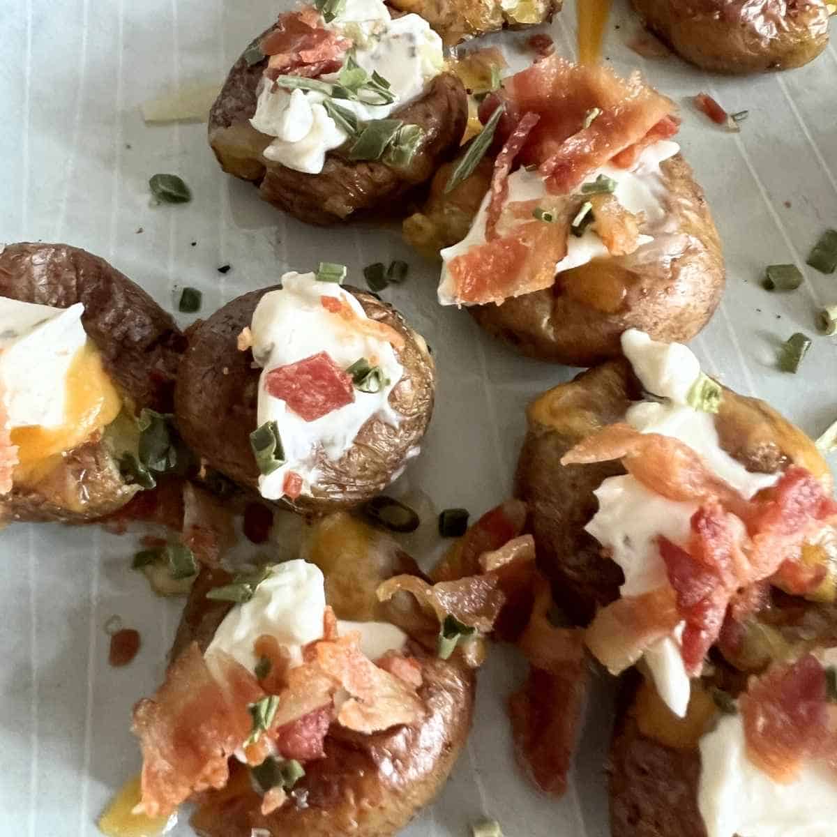 Mini baked potatoes topped with bacon, cream cheese, and chives. 