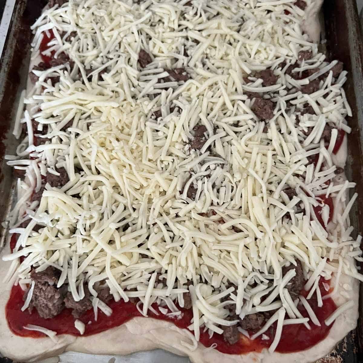 Cheese sprinkled on top of pizza.