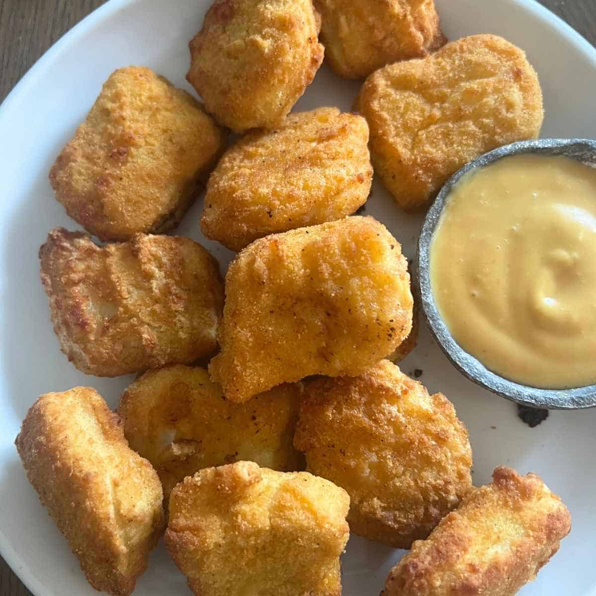Frozen chicken nuggets in air fryer with dipping sauce.