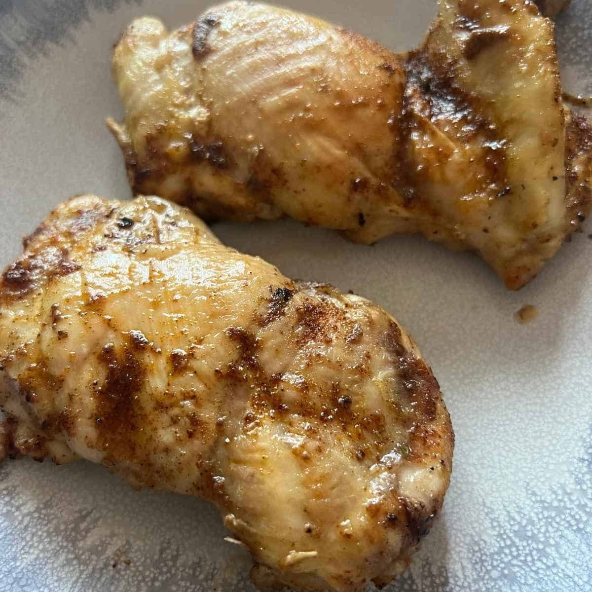 Frozen chicken thighs in air fryer basket.