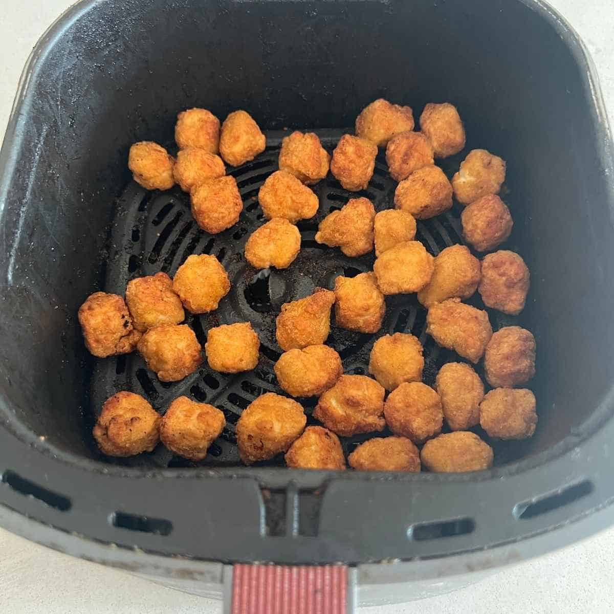 Popcorn chicken in air fryer basket. 