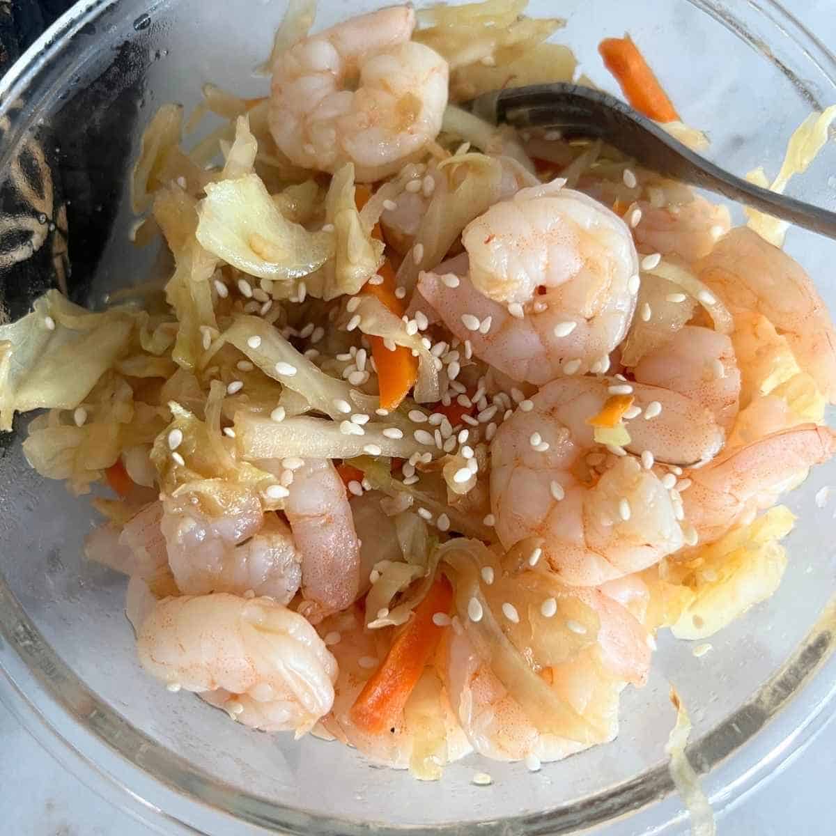 Shrimp egg roll in a bowl topped with sesame seeds.