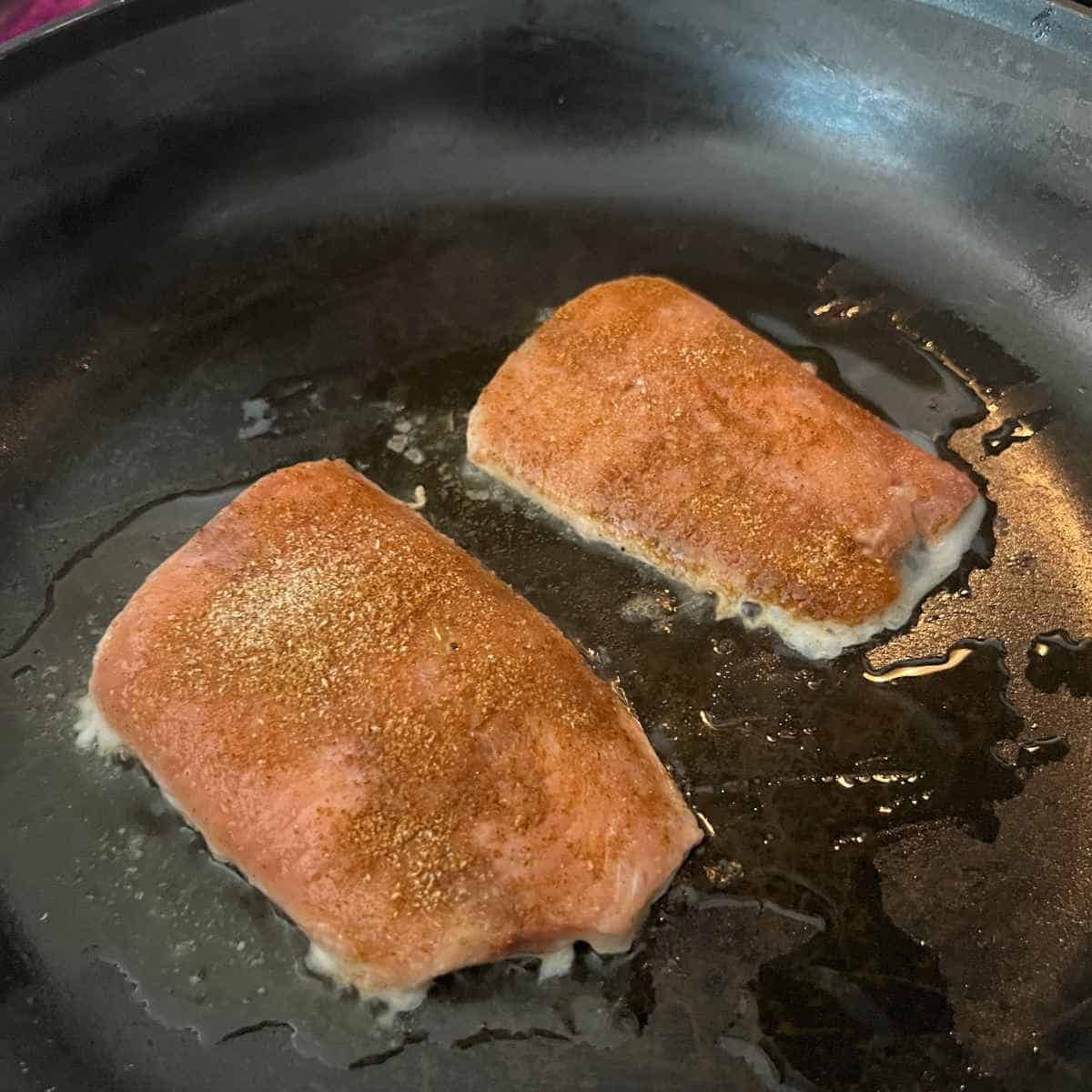 Seared salmon in skillet. 