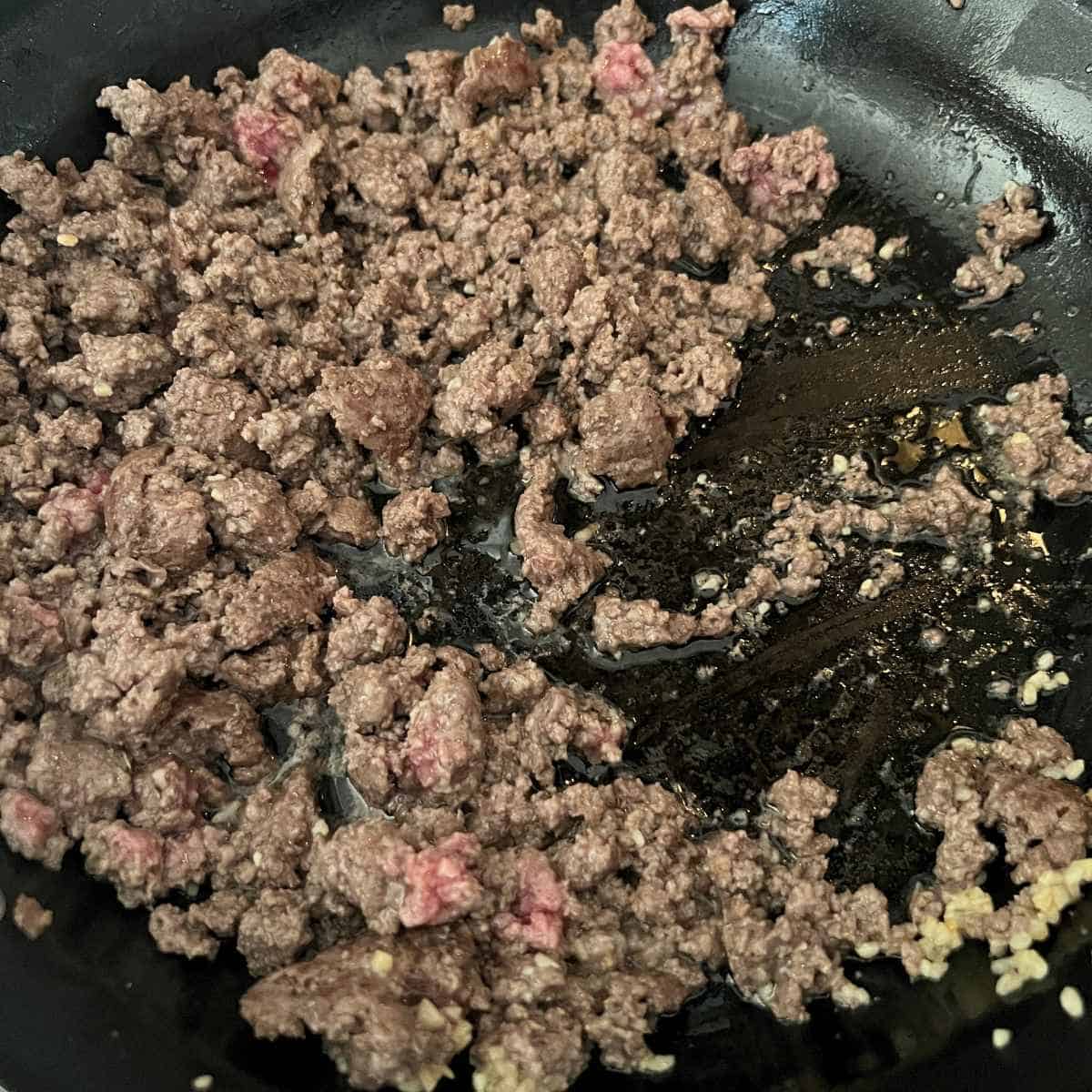 Cooked ground beef and aromatics in skillet.